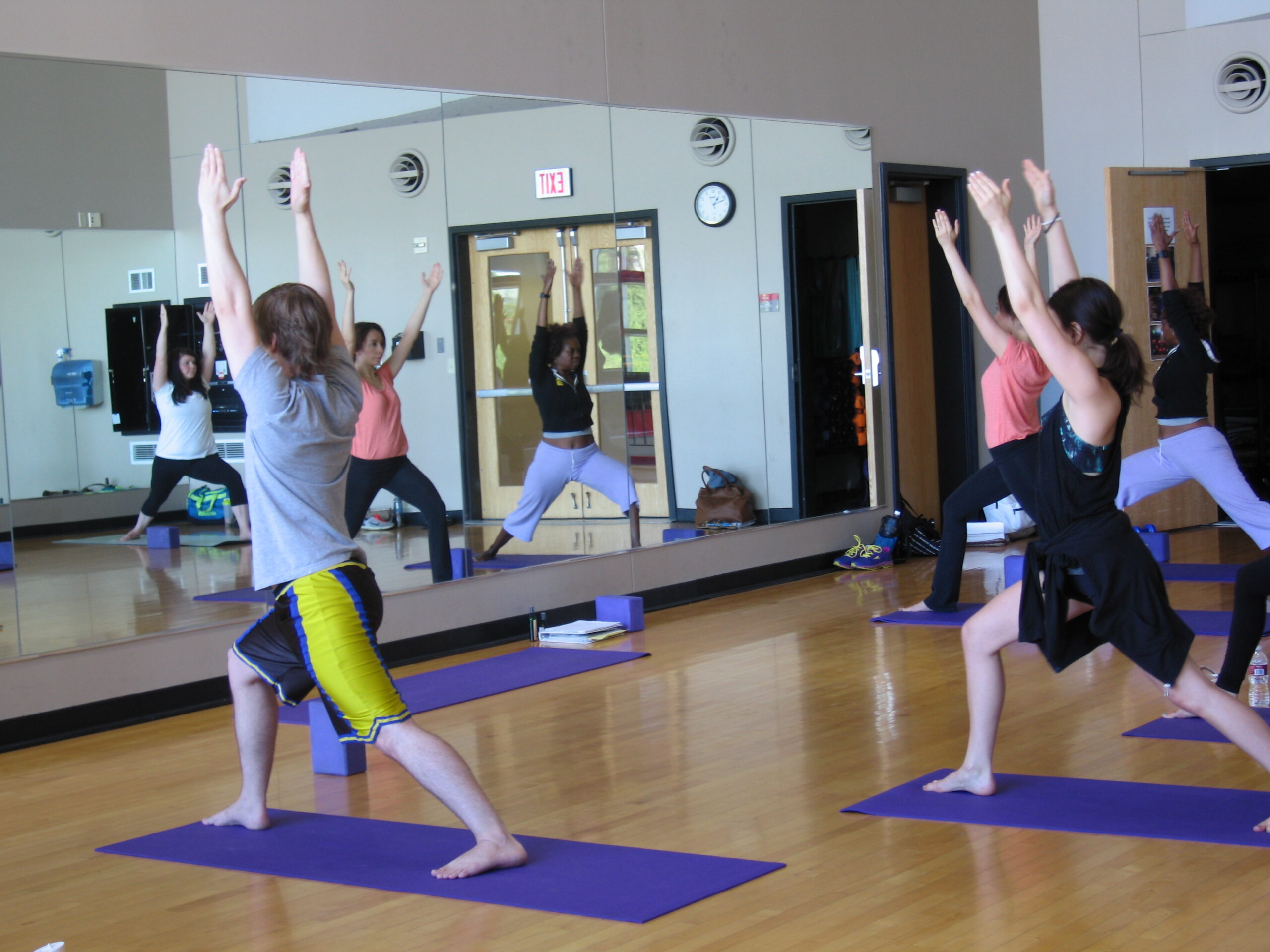 2 women practicing yoga while high fiving.